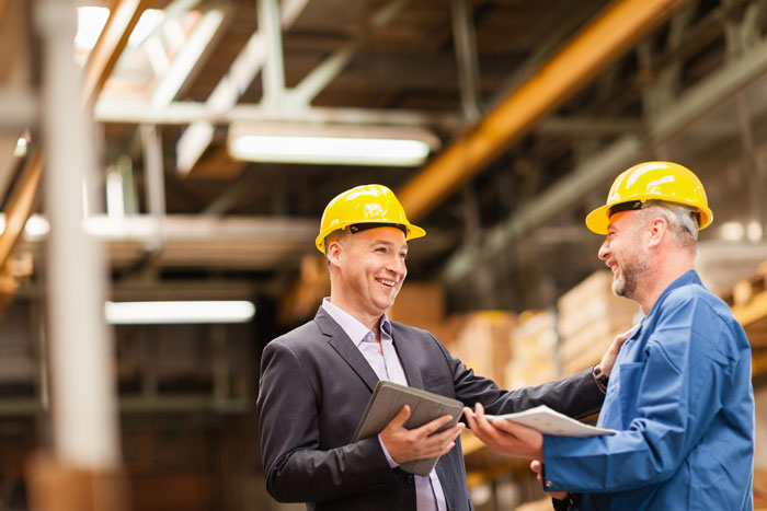 Smiling warehouse manager talking to worker