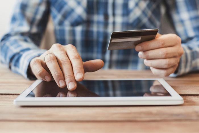 Businessman using tablet computer and credit card.