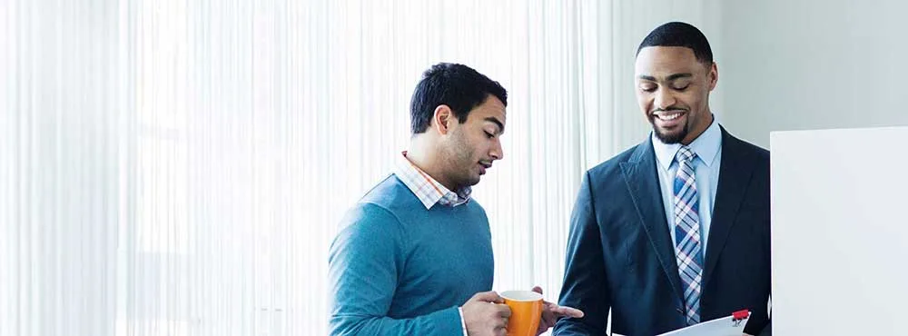 Businessmen discussing over document while standing in brightly lit office