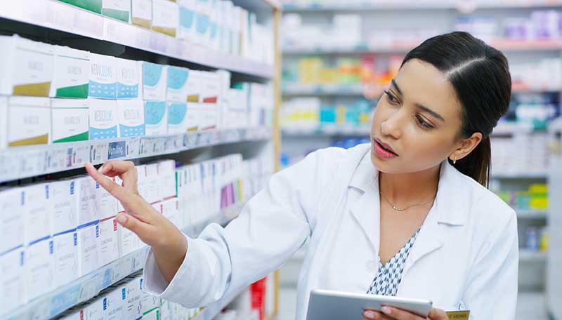 Shot of a young pharmacist using a digital tablet while working in a chemist