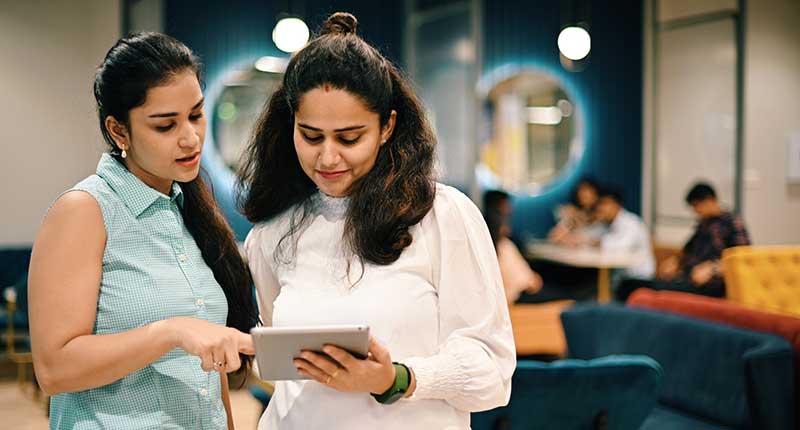 Two women discussing start-up business ideas in a co-working office.