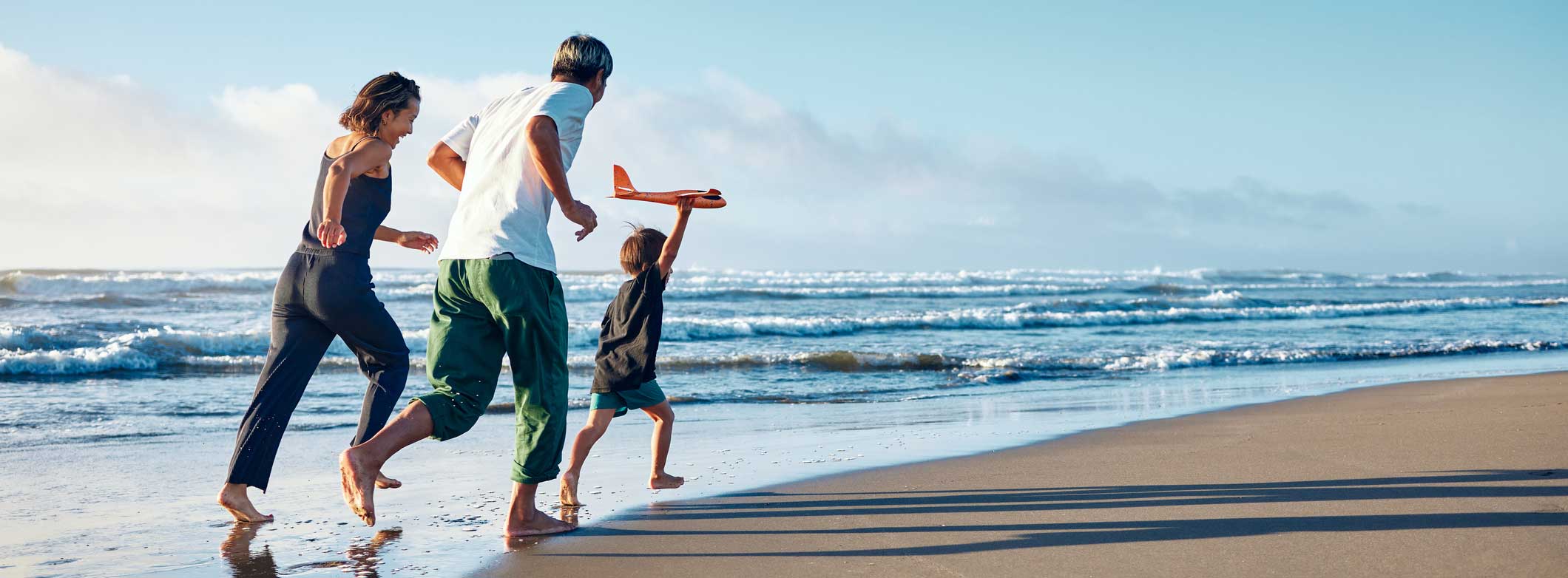 Back view of the family running along the coastline.