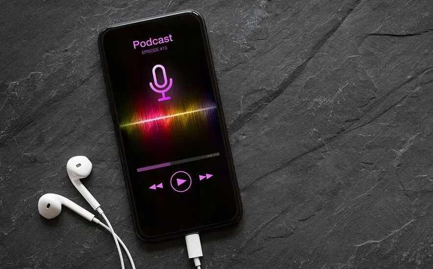 Earphones and mobile phone with podcast app on screen on black background